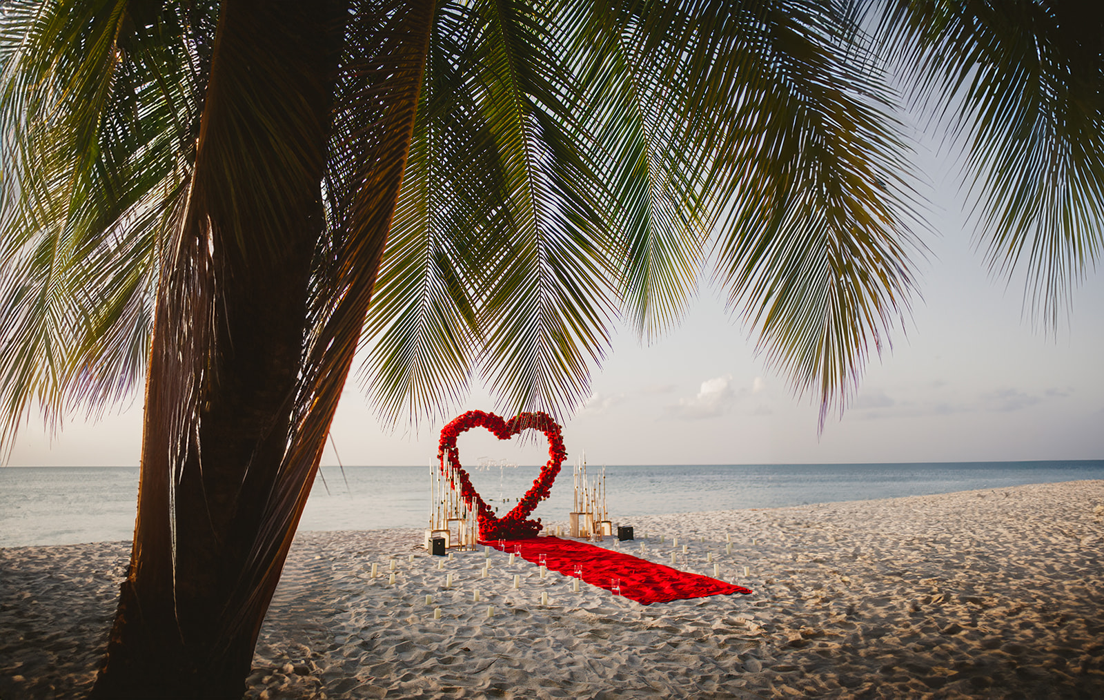 destination proposal in Tobago with red heart arch at Pigeon Point beach