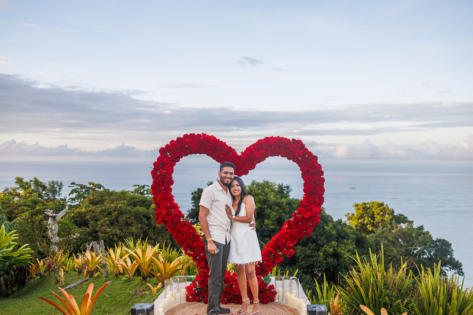 Hapy Couple Smiling in front of a Red Heart Arch after a Marriage Proposal at Mahogany Ridge Trinidad
